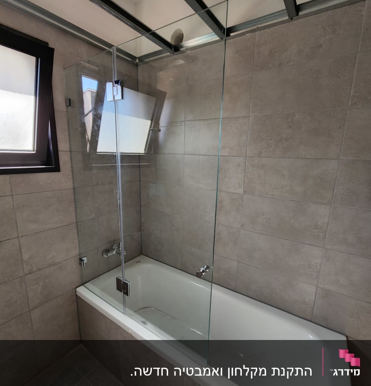 bathtub with glass shower screen and tiled walls